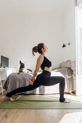 Flexible Frau, die sich beim Yoga in der Wohnung dehnt - MEUF03759