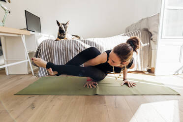 Frau übt Yoga auf einer Übungsmatte im Schlafzimmer einer Wohnung - MEUF03761