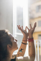 Frau mit erhobenen Händen beim Meditieren zu Hause - MEUF03769