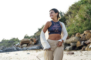 Smiling young woman looking away while running at beach - PGF00701