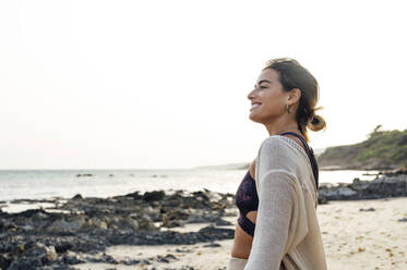 Smiling young woman looking at view from beach - PGF00705