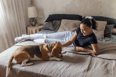 Vorpubertäres Mädchen mit Hund im Schlafzimmer zu Hause - EGHF00159