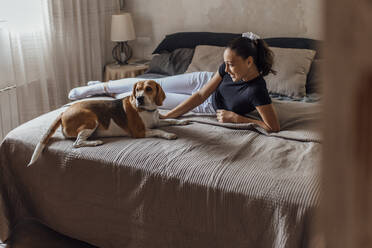 Mädchen liegt mit Hund auf dem Bett zu Hause - EGHF00160