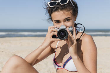 Woman photographing through camera at beach - JRVF01416