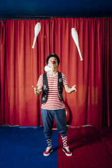 Männlicher Artist jongliert mit Stiften während einer Zirkusvorstellung - MEUF03821