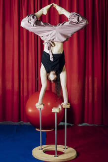 Weibliche Darstellerin streckt die Beine beim Handstand im Zirkus - MEUF03831