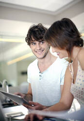 Smiling man sharing digital tablet with girlfriend at home - AJOF01559