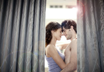 Romantisches junges Paar hinter einem Vorhang auf einem Balkon - AJOF01570