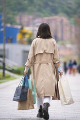 Young woman walking with shopping bags on footpath - SNF01507