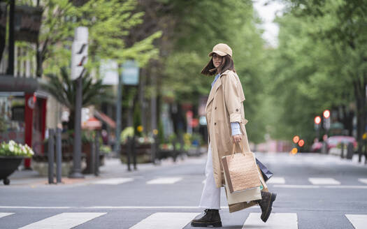 Young woman with shopping bags walking on road - SNF01512