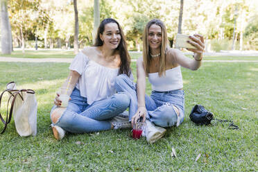 Lächelnde Freundinnen machen ein Selfie mit ihrem Smartphone im Park - JRVF01436