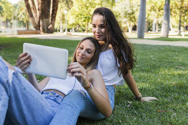 Junge Freundinnen benutzen ein digitales Tablet in einem öffentlichen Park - JRVF01443