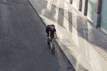 Junge Frontarbeiterin fährt mit dem Fahrrad auf der Straße - JRVF01484
