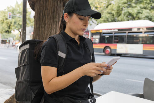 Frau mit Rucksack, die ein Mobiltelefon benutzt - JRVF01490