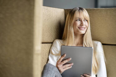 Businesswoman holding digital tablet looking away while day dreaming - PESF03085