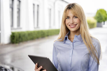 Lächelnde blonde weibliche Fachkraft hält digitales Tablet - PESF03106