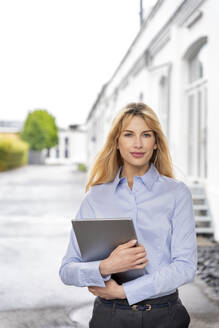 Junge blonde Frau, die ein digitales Tablet hält - PESF03109