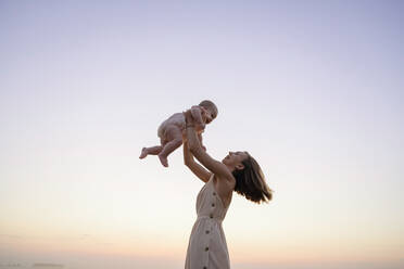 Happy mother playing with daughter during sunset - EYAF01722