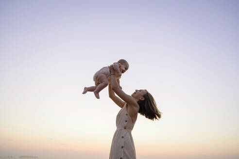 Glückliche Mutter spielt mit Tochter bei Sonnenuntergang - EYAF01722