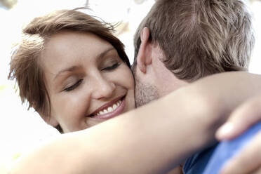 Smiling beautiful woman embracing boyfriend - AJOF01574