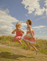 Girls playing with jumping rope at beach during sunny day - AJOF01587