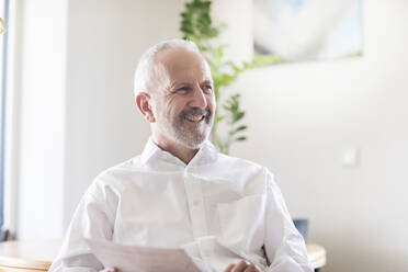 Smiling businessman looking away while sitting in office - SGF02865