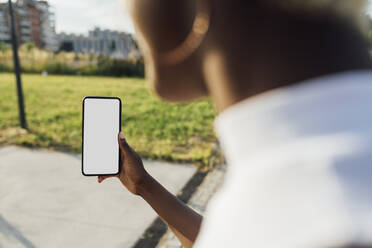 Junge Frau mit Smartphone auf dem Fußweg - MEUF03984