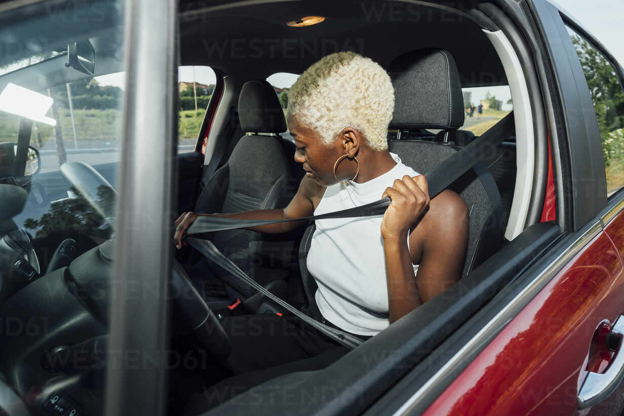 Frau schnallt sich im Auto sitzend an, lizenzfreies Stockfoto