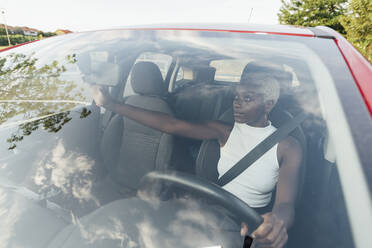 Woman adjusting rear mirror while driving car - MEUF04003