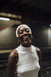 Cheerful woman standing at subway station - MEUF04019