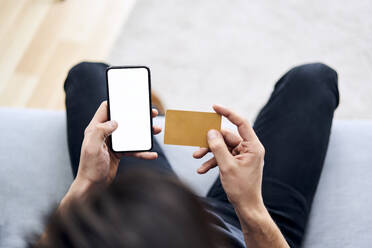 Mann beim Online-Bezahlen mit Kreditkarte und Smartphone - BSZF01817