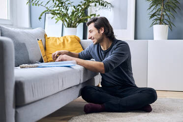 Männlicher Schüler beim Lernen mit dem Laptop zu Hause - BSZF01852