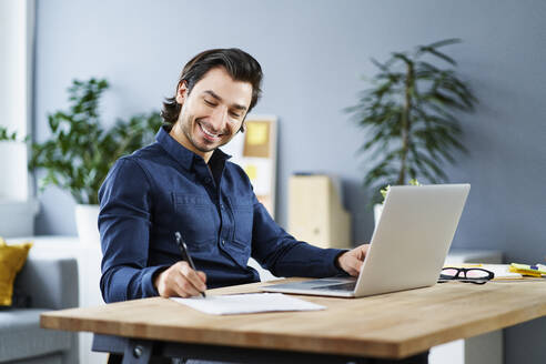 Smiling businessman signing contract at desk - BSZF01884