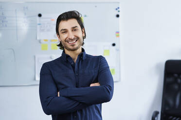 Smiling male professional with arms crossed at office - BSZF01894