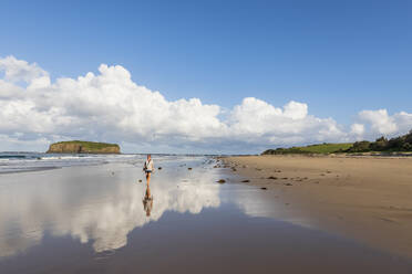 Weibliche Touristin, die am Strand von Minnamurra mit Stack Island im Hintergrund spazieren geht - FOF12136