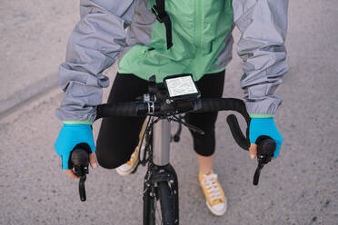 From above anonymous courier examining route on GPS map before riding bicycle on city street - ADSF28458