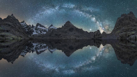 Atemberaubende Nachtlandschaft von rauen felsigen Bergen mit Schnee in der Nähe ruhigen See mit glatten Wasseroberfläche reflektierenden Himmel mit glänzenden Milchstraße - ADSF28464