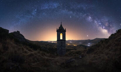 Amazing scenery with aged stone chapel in mountainous valley under evening sky with Milky Way and sunset light - ADSF28468