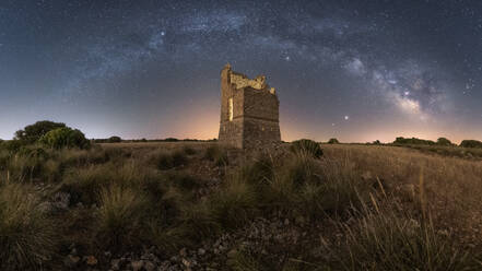 Picturesque scenery with remains of medieval stone building on hill under starry sky with Milky Way in twilight - ADSF28475