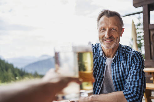 Lächelnder Mann stößt mit einem Freund an der Bar auf ein Bierglas an - DIGF16313