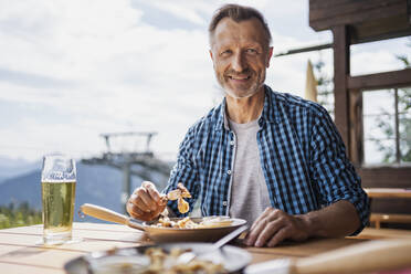 Lächelnder Mann beim Essen im Restaurant - DIGF16314