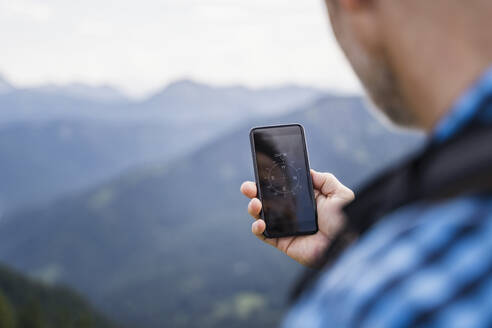 Männlicher Wanderer, der mit seinem Handy die Richtung sucht - DIGF16316