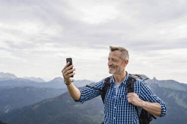 Smiling male backpacker taking selfie through mobile phone - DIGF16318