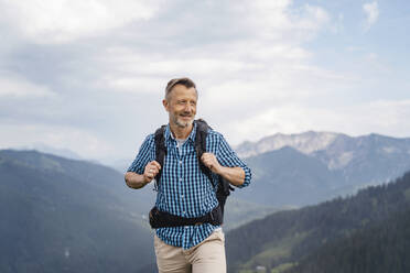 Älterer Mann mit Rucksack beim Wandern auf einem Berg - DIGF16336