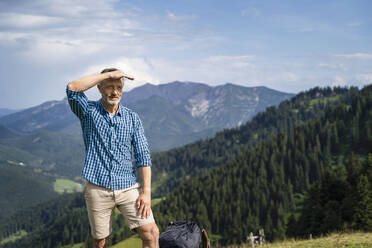 Männlicher Wanderer, der seine Augen abschirmt, während er auf einem Berg steht - DIGF16338