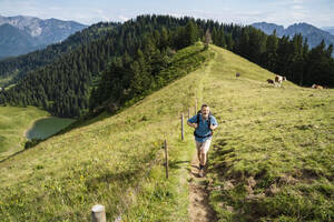 Männlicher Wanderer beim Wandern auf einem Bergpfad an einem sonnigen Tag - DIGF16340
