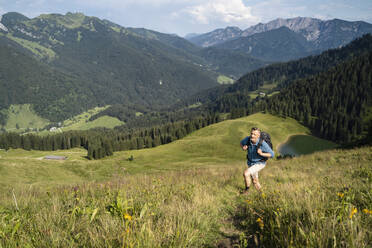 Männlicher Rucksacktourist beim Wandern auf einem Berg an einem sonnigen Tag - DIGF16345