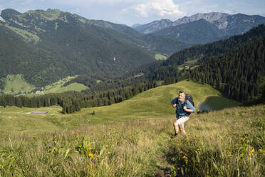 Male backpacker hiking up on mountain during sunny day - DIGF16345