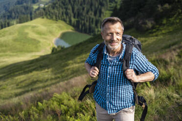 Lächelnder männlicher Rucksacktourist beim Wandern auf einem Berg - DIGF16347
