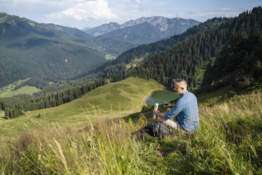 Männlicher Wanderer mit Blick auf den Berg an einem sonnigen Tag - DIGF16348